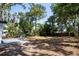 Backyard with a concrete patio with two white chairs under mature trees and grass at 8059 26Th N Ave, St Petersburg, FL 33710
