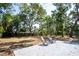 A backyard with two white chairs on a concrete patio and mature trees with dappled sunlight at 8059 26Th N Ave, St Petersburg, FL 33710