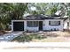 Charming home featuring a black garage door, complemented by white paint, black trim and a well-manicured lawn at 8059 26Th N Ave, St Petersburg, FL 33710