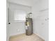 Compact utility room featuring a water heater, window with blinds, and white walls with light wood flooring at 8059 26Th N Ave, St Petersburg, FL 33710