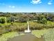 Aerial view displays waterfront dock with benches that leads to lily pads and a community in the distance at 9293 Rally Spring Loop, Wesley Chapel, FL 33545