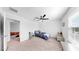Bright bedroom with neutral carpet, ceiling fan, and a gray upholstered bench at 9293 Rally Spring Loop, Wesley Chapel, FL 33545