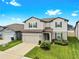 Charming two-story home showcasing landscaped front yard, gray exterior, and an attached two-car garage at 9293 Rally Spring Loop, Wesley Chapel, FL 33545