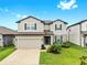 Charming two-story home showcasing landscaped front yard, gray exterior, and an attached two-car garage at 9293 Rally Spring Loop, Wesley Chapel, FL 33545