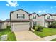 Charming two-story home showcasing landscaped front yard, gray exterior, and an attached two-car garage at 9293 Rally Spring Loop, Wesley Chapel, FL 33545