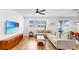 Bright living room featuring hardwood floors, sectional sofa, large window, and wall-mounted TV for a modern and inviting space at 9293 Rally Spring Loop, Wesley Chapel, FL 33545