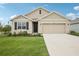 Charming single-Gathering home featuring a two-car garage, well-manicured lawn, and neutral-toned exterior at 10233 Opaline Sky Pl, Riverview, FL 33578