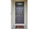A close-up of a gray front door, digital lock, and seasonal poinsettia doormat at 10233 Opaline Sky Pl, Riverview, FL 33578