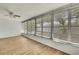 Bright sunroom features wood-look flooring, multiple windows with backyard views and a ceiling fan at 11130 White Oak Ln, Port Richey, FL 34668