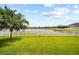 Expansive backyard with vibrant green grass and a white picket fence bordering a tranquil lake at 11522 Sunburst Marble Rd, Riverview, FL 33579
