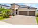 Charming single Gathering home featuring a three-car garage, stone accents, and meticulously landscaped front yard at 11522 Sunburst Marble Rd, Riverview, FL 33579