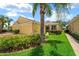 A bright yellow home with a two-car garage, green lawn, and vibrant landscaping with palm trees under a clear blue sky at 11559 Captiva Kay Dr, Riverview, FL 33569