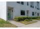 Modern townhome featuring a light-colored exterior, green door with wreath, and manicured landscaping at 1330 W Gray St # 1, Tampa, FL 33606