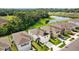 A home is shown from above near a lush pond surrounded by verdant greenery and neighborhood homes at 13686 Whiskey Daisy Dr, Dade City, FL 33525