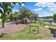 Community playground with a swing set, slides, and shade trees for outdoor fun at 13686 Whiskey Daisy Dr, Dade City, FL 33525