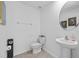 A simple half-bathroom features a round mirror, pedestal sink, and standard toilet at 13686 Whiskey Daisy Dr, Dade City, FL 33525