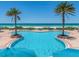 Beautiful pool with palm trees along the perimeter and view of the white sand beach and ocean beyond at 1520 Gulf Blvd # 1505, Clearwater Beach, FL 33767