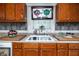 Close-up of kitchen sink, countertop, wood cabinets and unique artwork above the window at 1683 Pine St, Largo, FL 33774