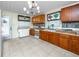 Well-lit kitchen area featuring wood cabinets, tile flooring and door to backyard at 1683 Pine St, Largo, FL 33774