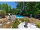 A beautiful, bright blue pool is surrounded by mature trees and statuary at 1683 Pine St, Largo, FL 33774