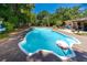 A blue in-ground pool with a white rim surrounded by a deck and greenery at 1683 Pine St, Largo, FL 33774
