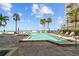 Relaxing outdoor pool with sun loungers, swaying palm trees, and ocean views in a sunny setting at 17710 Gulf Blvd # 304, Redington Shores, FL 33708
