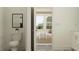 Bathroom with toilet, framed art, and doorway view to bedroom with neutral tones and natural light at 18154 Serene Lake Loop, Lutz, FL 33548