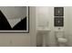 Bathroom featuring sleek pedestal sink, modern mirror, and a toilet with tasteful framed art at 18154 Serene Lake Loop, Lutz, FL 33548