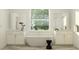 Bright bathroom featuring a soaking tub under a large window, with double vanities and modern fixtures at 18154 Serene Lake Loop, Lutz, FL 33548