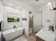 Well-lit bathroom boasts a freestanding tub, walk-in shower, and contemporary fixtures for a luxurious experience at 18577 Clay Hill Rd, Dade City, FL 33523