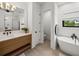 Bright bathroom with a soaking tub, wood vanity, and modern fixtures at 18577 Clay Hill Rd, Dade City, FL 33523