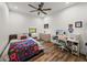Bedroom is spacious and features a bed with a colorful blanket, a desk, and wood flooring at 18577 Clay Hill Rd, Dade City, FL 33523
