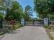 Elegant black fence gate with stone pillars and decorative lanterns marking the driveway entrance at 18577 Clay Hill Rd, Dade City, FL 33523