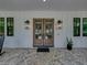 Inviting porch with double doors, stylish lanterns, and decorative brick paving at 18577 Clay Hill Rd, Dade City, FL 33523