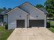 Exterior of a modern home showcasing its two-car garage with dark doors at 18577 Clay Hill Rd, Dade City, FL 33523