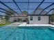 Backyard pool area features a screened-in pool and patio with modern white facade at 18577 Clay Hill Rd, Dade City, FL 33523
