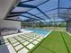 Outdoor space with a screened-in pool area with artificial turf, outdoor kitchen, and stone tile at 18577 Clay Hill Rd, Dade City, FL 33523