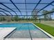 Screened in pool with seating ledge and lush green space in the background at 18577 Clay Hill Rd, Dade City, FL 33523