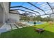 Screened-in pool area featuring an outdoor kitchen, lounge chairs, and lawn games at 18577 Clay Hill Rd, Dade City, FL 33523