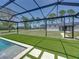 Screened-in pool with artificial turf, tile, and adjacent outbuilding at 18577 Clay Hill Rd, Dade City, FL 33523