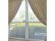 A window view from inside the house, peering out through the blinds, overlooking a lush, green landscape at 1922 Sassafras Dr, Wesley Chapel, FL 33543