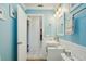 Updated bathroom with bright blue walls, white wainscoting, and a sink with white cabinetry at 202 Grayson Ct, Sun City Center, FL 33573