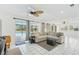 Open-concept living room boasts natural light with a neutral sectional couch and access to the pool area at 202 Grayson Ct, Sun City Center, FL 33573