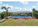 Beautiful backyard featuring a screened-in pool and tropical palm trees at 202 Grayson Ct, Sun City Center, FL 33573