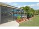 Beautiful screened-in pool surrounded by lush landscaping and a spacious patio area at 202 Grayson Ct, Sun City Center, FL 33573