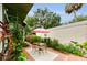 Cozy backyard featuring brick-paved area with an outdoor dining set under an umbrella, surrounded by lush plants at 214 Scotland St, Dunedin, FL 34698