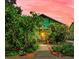 Charming home with lush, vibrant landscaping surrounding the entrance and walkway at 214 Scotland St, Dunedin, FL 34698