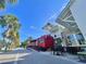 Quaint street view with palm trees, outdoor seating, and a red food cart adding charm to the community at 214 Scotland St, Dunedin, FL 34698