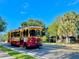 A vintage-style trolley car travels along a street lined with lush trees at 214 Scotland St, Dunedin, FL 34698