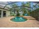 Inviting screened-in pool with a unique shape, featuring a small waterfall and surrounded by lush landscaping at 2146 Gold Dust Ct, Trinity, FL 34655
